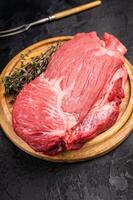 Raw Silverside Round beef meat piece , fresh bottom round on wooden board. black background. Top view photo