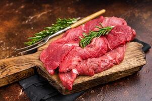 Beautifully arranged raw horse meat slices on a wooden platter, showcasing its appealing color and texture, perfect for cooking inspiration. brown background. top view photo