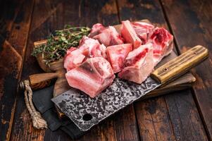 Raw diced Beef meat with bones for stew or goulash on wooden board. wooden background. top view photo