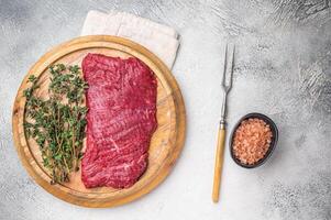 Flank steak, raw beef meat with herbs for frying. grey background. top view photo