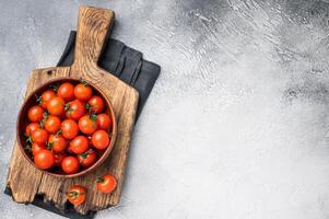 Plump cherry tomatoes, glistening under natural light, highlighting their freshness. Perfect for adding a burst of flavor to any recipe. grey background. top view photo