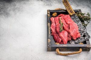 Raw horse meat slices in a wooden tray, showcasing its appealing color and texture, ready for cooking. grey background. top view photo