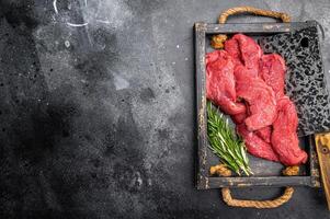 Vibrant raw bison meat pieces on a butcher block, illustrating the allure of this lean protein source for health-conscious culinary enthusiasts. black background. top view photo