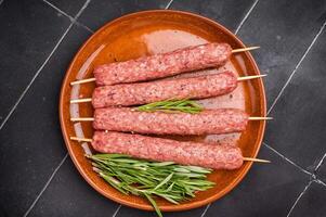 Raw Cevapcici skewers, Cevapi sausages from mince beef and pork meat. black background. top view photo