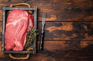 Unccoked Top Round beef, raw topround roast meat with thyme. wooden background. Top view photo