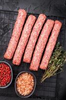 Uncooked Raw Cevapcici Sausage, fresh Cevapi from mince beef and pork meat on a rack. black background. top view photo