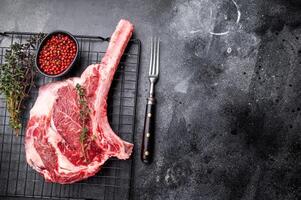 Uncooked tomahawk steak, raw black angus beef rib eye with bone. black background. top view photo
