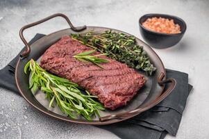 Grilled Flank or Flap steak, BBQ beef meat with thyme and spices on plate. grey background. top view photo