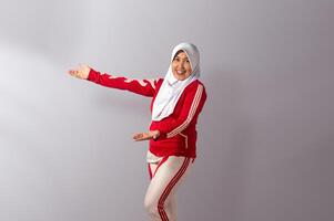 Smiling Muslim Woman in Sportswear Presenting or Introducing with Open Hands photo