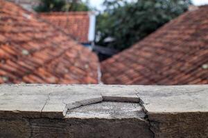 Cracked Concrete Surface with Blurred Roof Tiles in the Background photo