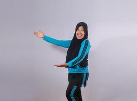 Smiling Muslim Woman in Sportswear Posing with Open Arms on Plain Background photo