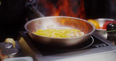 Female hands in black disposable gloves set fire to the contents of a frying pan during cooking, close-up video