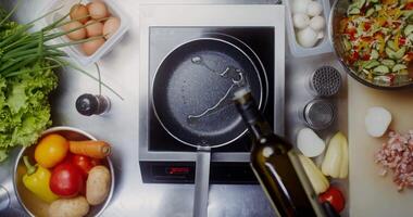 A woman with disposable black gloves on her hands pours oil on a frying pan standing on the stove, a close-up of her hands, top view video