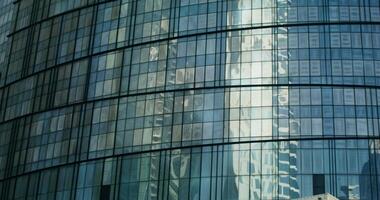 The glass facade of a modern semicircular skyscraper with sunlight reflected in the windows video