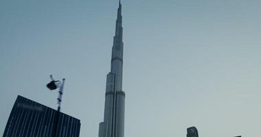 Top of the Burj Khalifa shining with lights at dusk, of evening Dubai from a moving car window video