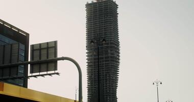 Construction of a skyscraper of irregular shape, cranes and construction equipment on the roof of an unfinished building video