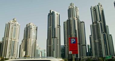 Modern glass minimalistic skyscrapers in the center of a densely populated city with palm trees at the foot, a view from below in motion video
