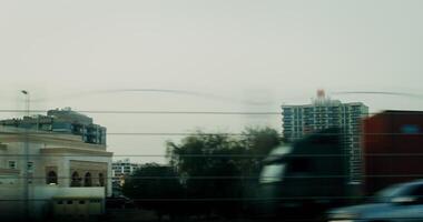 View from the window of a car moving along a busy road to the street of a modern city with a mosque and residential buildings video