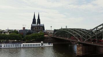 Eisenbahn Brücke mit ein Zug ziehen um Über es von ein Vogel Auge Sicht. Panorama- Schießen von ein Drohne, Aussicht von das historisch Center von Köln, Deutschland. video