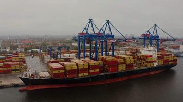 Arial view on a barge loaded with containers for international shipping, moored in an industrial port, Klaipeda, Lithuania. Drone . video