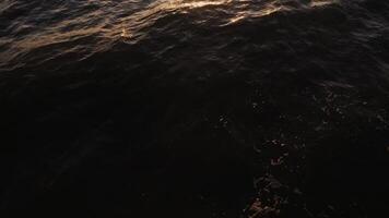 Golden sunlight reflected in dark sea water, top view. from a drone, view of the sea waves, no land. video