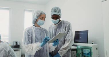 Colleagues of different nationalities communicate and use a digital tablet during a working day in a modern laboratory. 4k , red komodo video