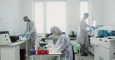 A team of scientific researchers work in a modern laboratory using microscopes, computers and modern medical equipment. 4k , red komodo video