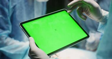 Doctor's hands in rubber gloves use a tablet with a green screen, close-up. Chroma key, mockup, copy space. in 4k, red komodo video