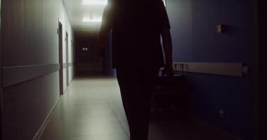 A doctor walks past a hospital gurney with an oxygen bottle left on it, standing in the hallway of the hospital. in 4k, red komodo video