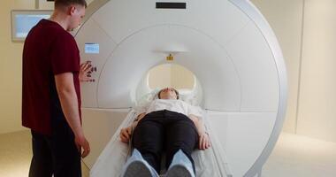 a médico prensas uma botão em a ct Varredura ao controle painel, enviando a paciente para dentro a túnel para cérebro mri . dentro 4k, vermelho Komodo video