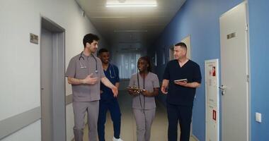 A group of doctors chatting cheerfully as they walk down the corridor of the medical center. Colleagues of various nationalities. in 4k, red komodo video