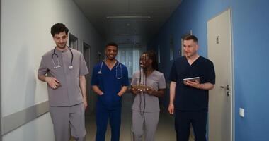 Colleagues of different nationalities smile and talk while walking along the corridor of the hospital. Doctors in uniform. in 4k, red komodo video
