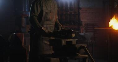 A blacksmith in protective gear and goggles saws off part of a metal workpiece using a flex, metal sparks fly in different directions, close-up, dynamic . 4k , red komodo video