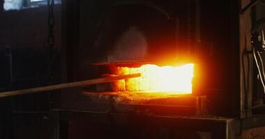 A blacksmith places a metal blank in a burning furnace, close-up of burning fire, man's face is not visible, an unrecognizable person. Blacksmith workplace, iron forging workflow. 4k , red komodo video