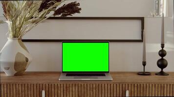 An open laptop with a green screen stands on a table in a stylish home interior. Chroma key, mockup, copy space. in 4k, red komodo video