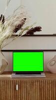 Copy space, open laptop with green screen stands on the table in stylish home interior, vertical . Color key, layout. 4k , red komodo video