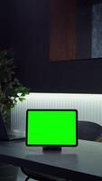 Tablet with green screen stands on the desktop of a young businesswoman using a mobile phone passing in the background, chroma key, copy space, mockup. in 4k format, red komodo. video
