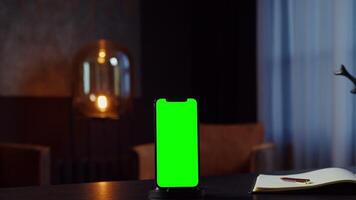 A mobile phone with a green screen stands on the desktop of a young businesswoman talking on the phone while walking in the office, chroma key, copy space. in 4k format, red komodo. video