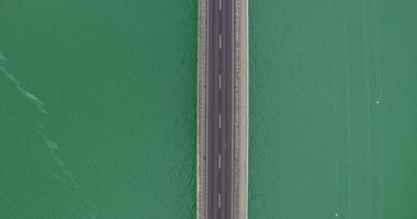 View from above, a narrow road bridge without cars, over a river with small ripples of waves. recording from a drone video