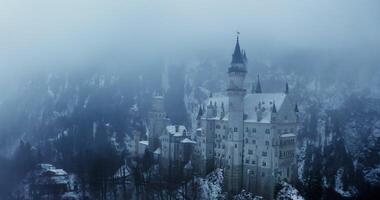 Overview of Hohenzollern Castle from a dynamic motion quadcopter, bird's eye view close-up footage on a winter day. Foggy haze over castle, located on top of a hill overgrown with spruce forest video