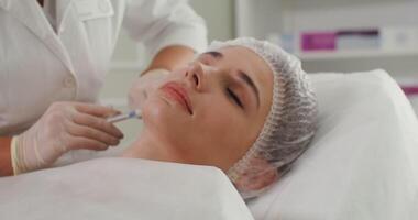 Introduction of plasma injections into the skin of the face of a female patient. Close-up, shifting from the patient's face to the doctor. Plasma therapy, injection treatment. in 4k, red komodo video