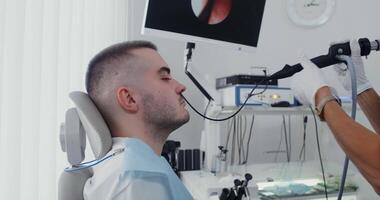 An ENT woman examines the patient's sinuses using a medical mini camera, inserting it into the nostril. Treatment of the respiratory system in a modern clinic. in 4k, red komodo. video