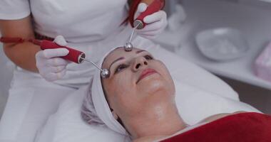 The procedure for smoothing mimic wrinkles using a laser. Facial skin massage using modern equipment in a cosmetology clinic. in 4k, red komodo video