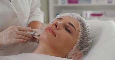 Close-up of the face of a female patient during the injection of plasma into the skin during treatment. Plasmotherapy, injection treatment in modern cosmetology. in 4k, red komodo video