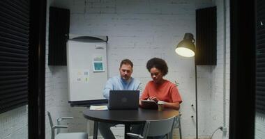 Young entrepreneurs work in a meeting room using modern wireless technology and discussing a project that a colleague has brought to their office. Teamwork on a startup video