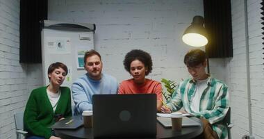 A group of young entrepreneurs of various nationalities chatting on a laptop while sitting at a table in a modern office. Online training during the creation of a new business video