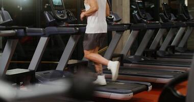 A young man of European appearance, athletic build, runs on treadmill, looking intently at the digital display. State-of-the-art gym equipment for exercise, health and sports, hobbies and lifestyle video