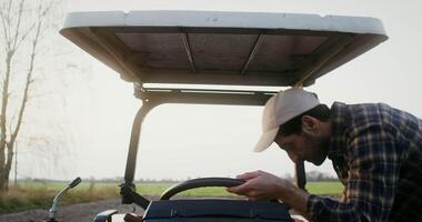 Close-up front view of a tractor driver, getting behind the wheel of an agricultural machine with an open cab and starting to move on it video