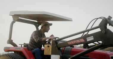 A young male farmer of European appearance turns a tractor, moving to a new lane while plowing an agricultural field on an autumn day video