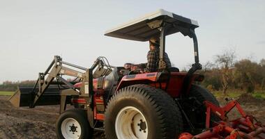 A young European-looking farmer turns a tractor around and begins to drive along a new row, plowing a field on an autumn day and turns around, checking the quality of work video